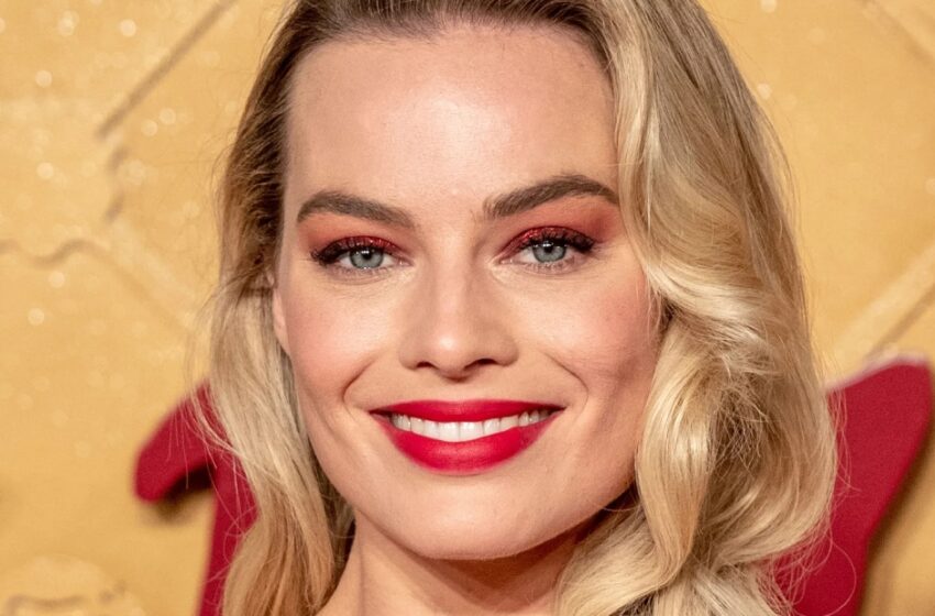  La embarazada Margot Robbie en Cerdeña se desabrochó la camisa, mostrando su vientre redondeado.